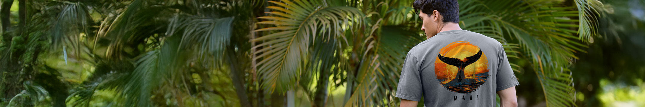Person wearing a gray t-shirt with a whale design in a tropical setting