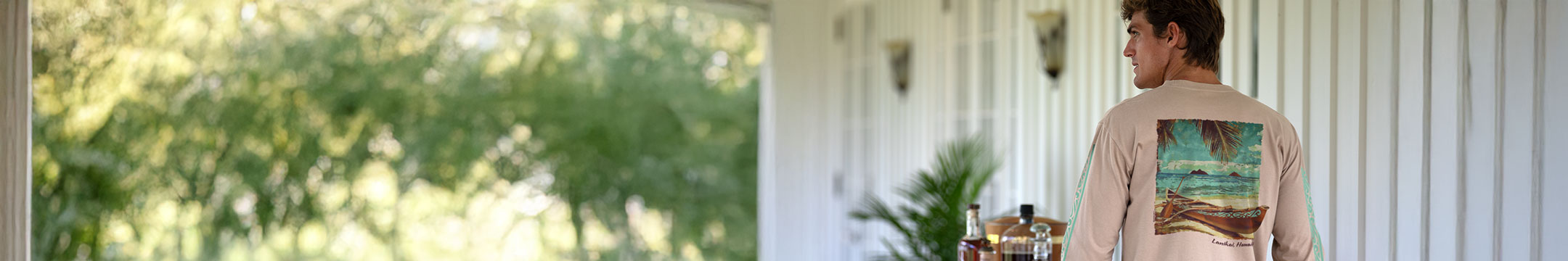 Person standing outdoors with a scenic background wearing a kona coffee dyed long sleeve with a beach graphic on the back