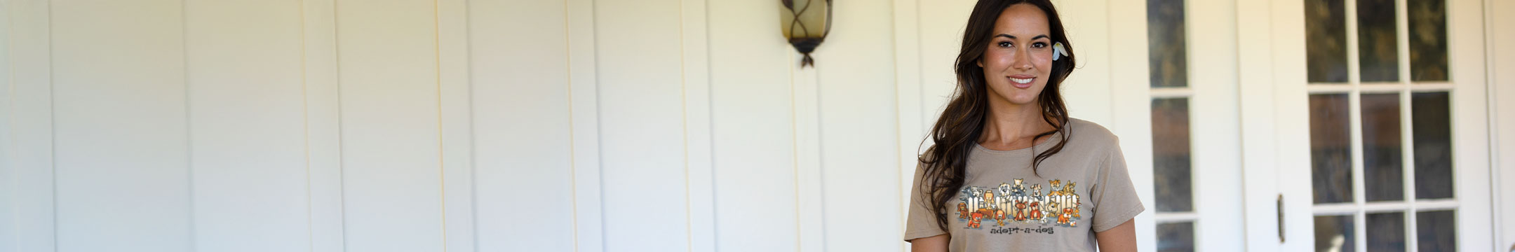 Woman wearing a t-shirt with a graphic design in front of a white door.