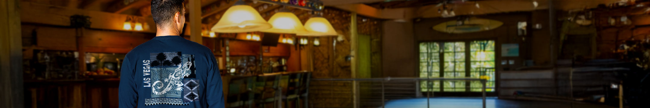 Man standing in a room inside wearing a navy shirt with a gecko design
