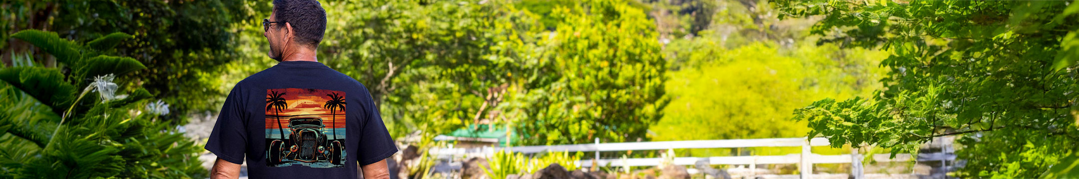 Person wearing a black t-shirt with a colorful design, standing in a lush green outdoor setting.