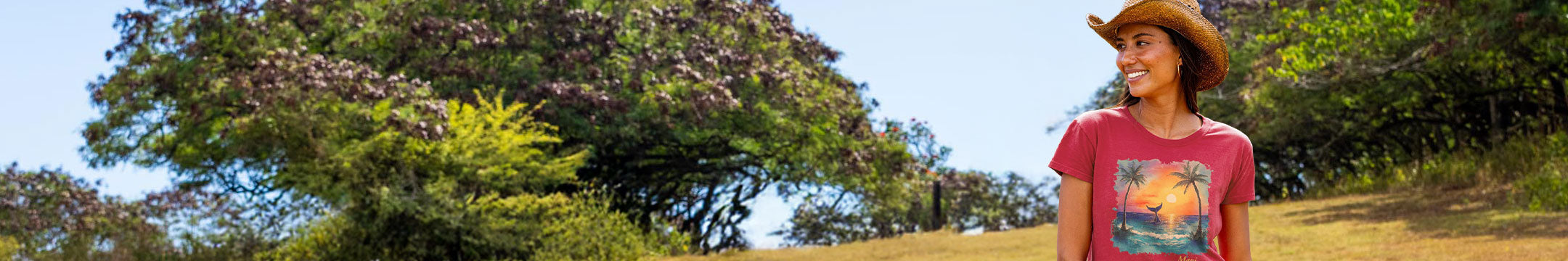 Woman in a raspberry dyed shirt with a whale design standing outdoors among trees