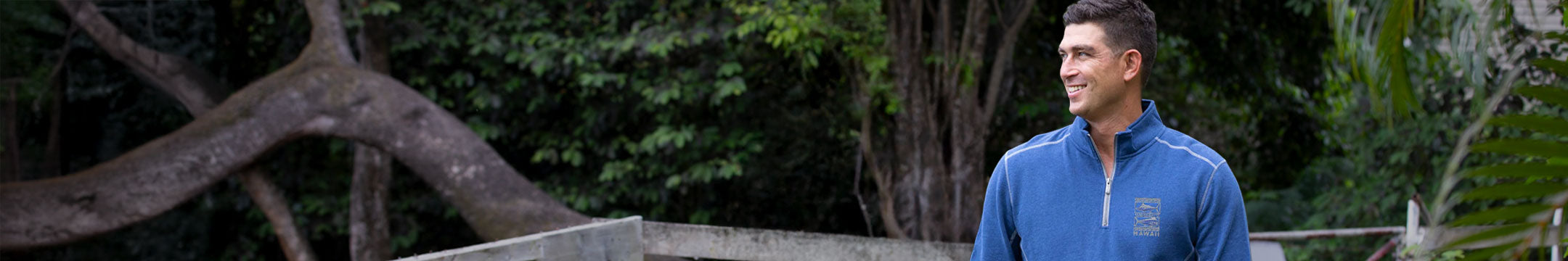 Man in a blue jacket standing outdoors with trees in the background