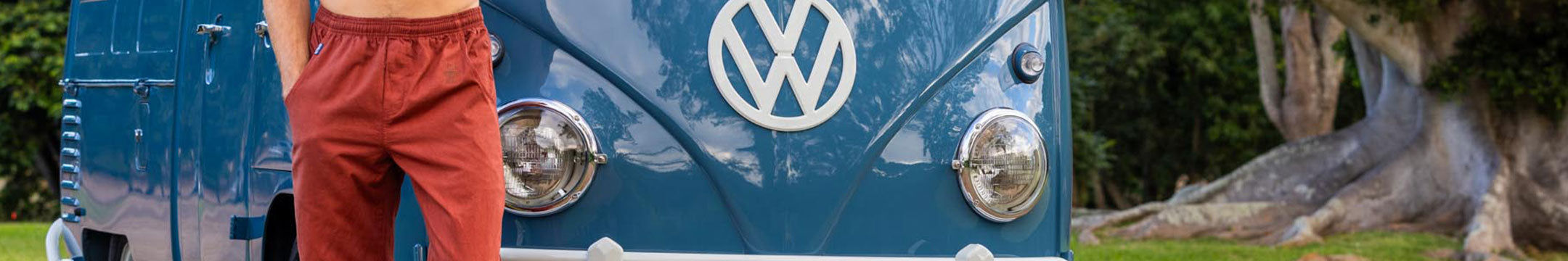 Person wearing Whiskey Dyed pants standing next to a blue Volkswagen van with trees in the background