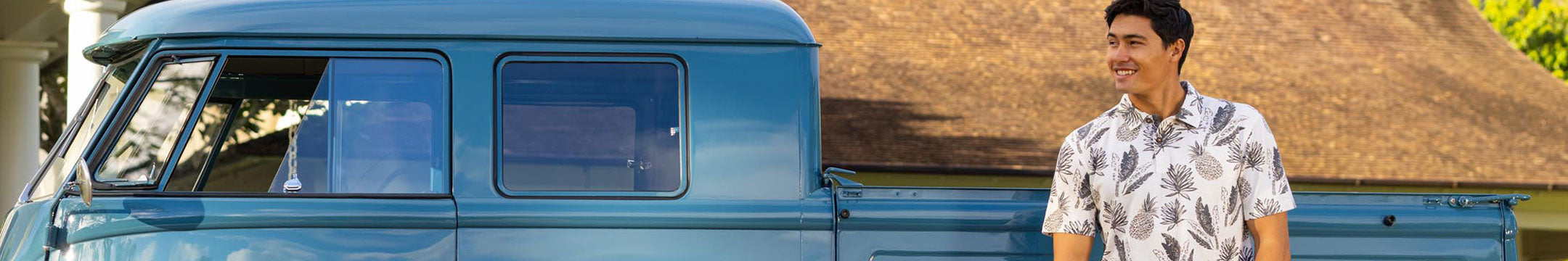 Man standing on a grassy area with a body of water and mountains in the background