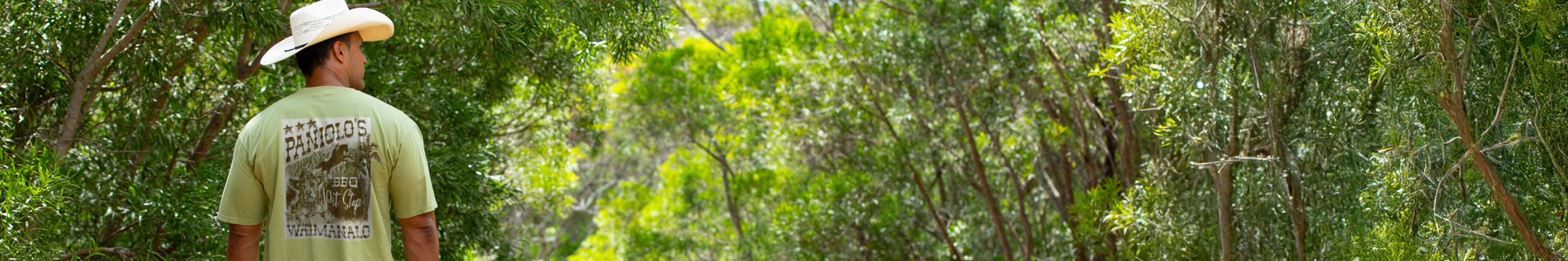 Person wearing a cowboy hat and Hemp Dyed green shirt walking through a forest