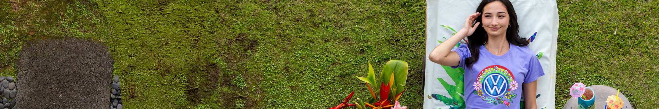 Woman wearing a Lavender Dyed shirt with a nature-themed design, sitting on a white chair outdoors.