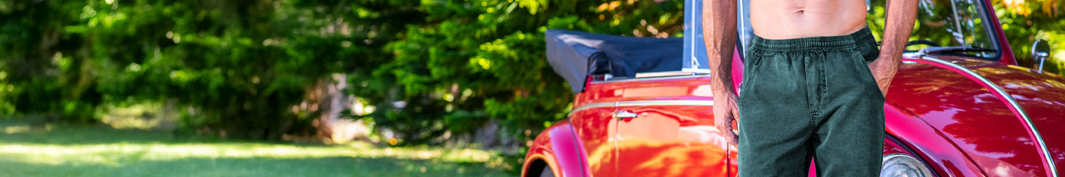 Man wearing Pine Dyed twill pants standing in front of a vintage car