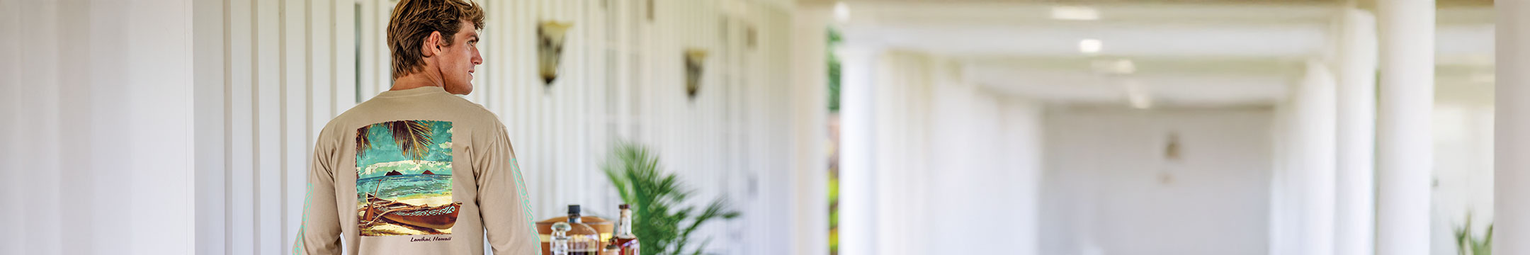 Man walking through a sunlit room with a decorative wall piece.