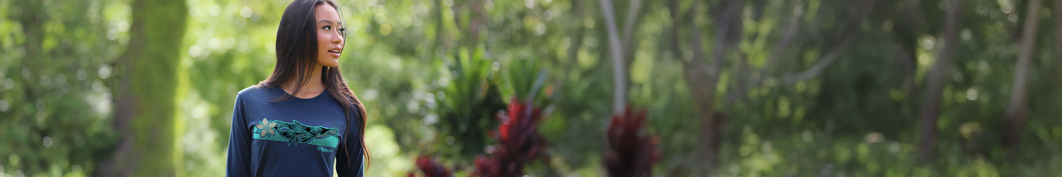 Woman standing outside wearing a navy long sleeve shirt with a whale print on the front