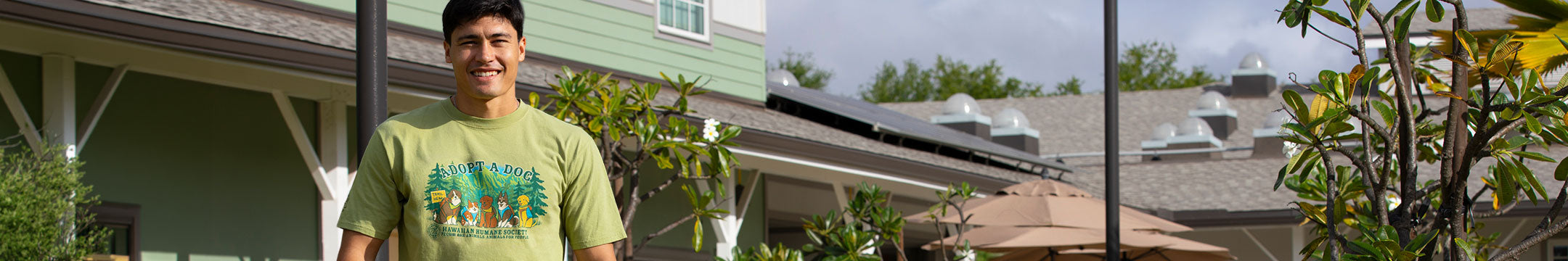 Person wearing a green t-shirt with nature-themed design standing in front of a house.