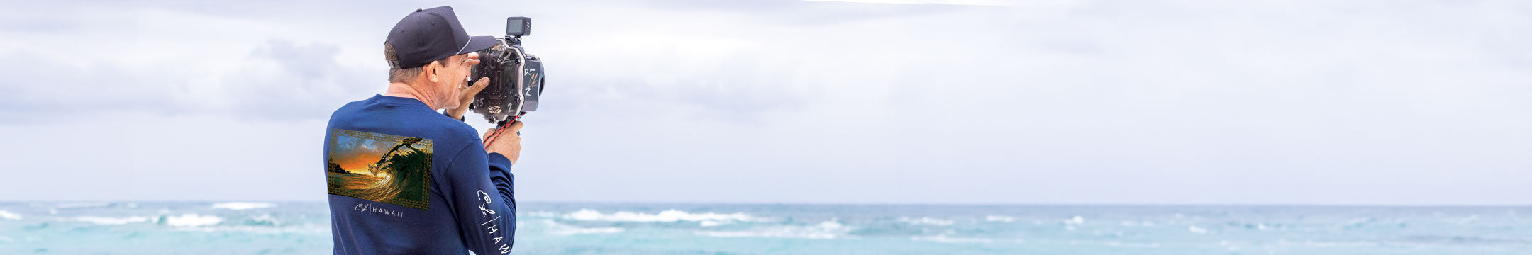 man standing on  the beach with his camera taking photos of the ocean