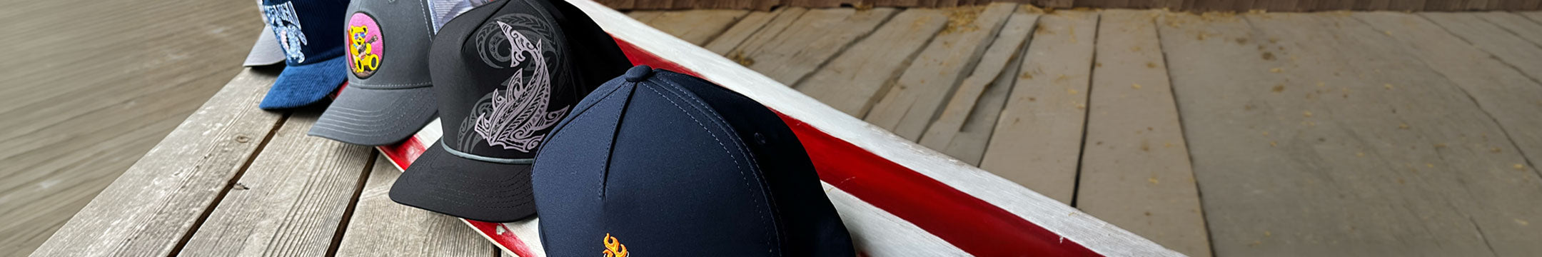 Hats sitting on a wooden dock with a red stripe in the background