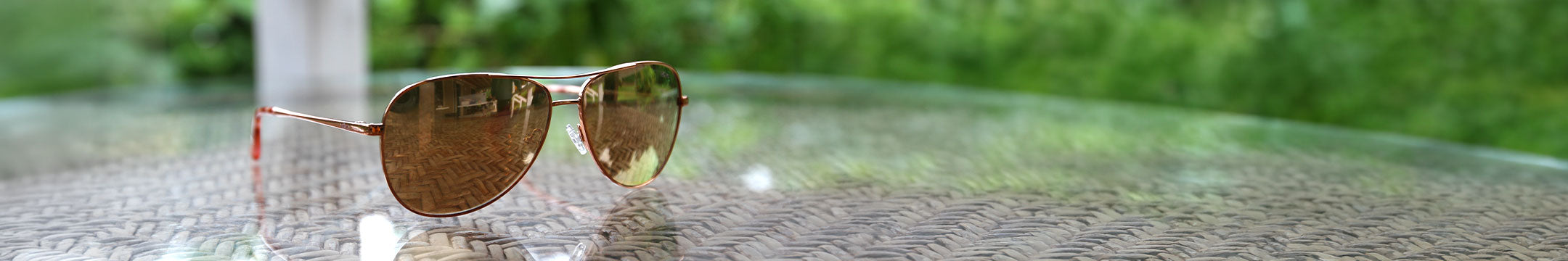 A pair of sunglasses outdoors on a glass tabletop