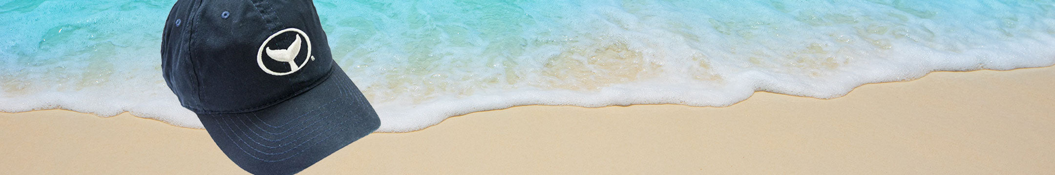 Black cap with a logo on a beach with waves