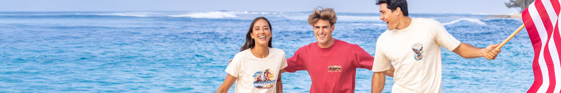 Three people standing on a beach with a clear blue sky and ocean.