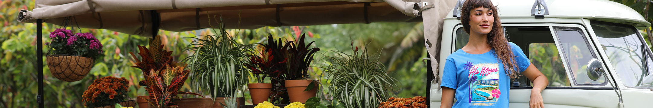 Plant stand with plants and a person wearing a blue t-shirt in front of a van.