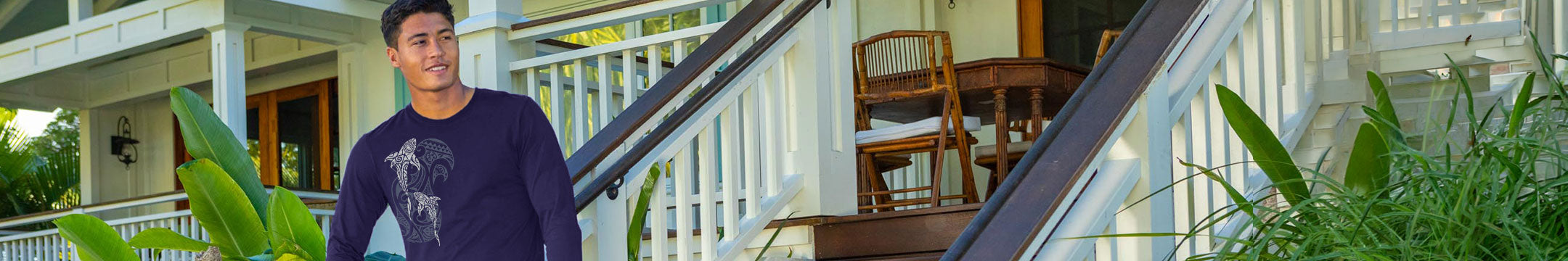 Man standing near a front porch wearing a dark blue long sleeve  with a shark design