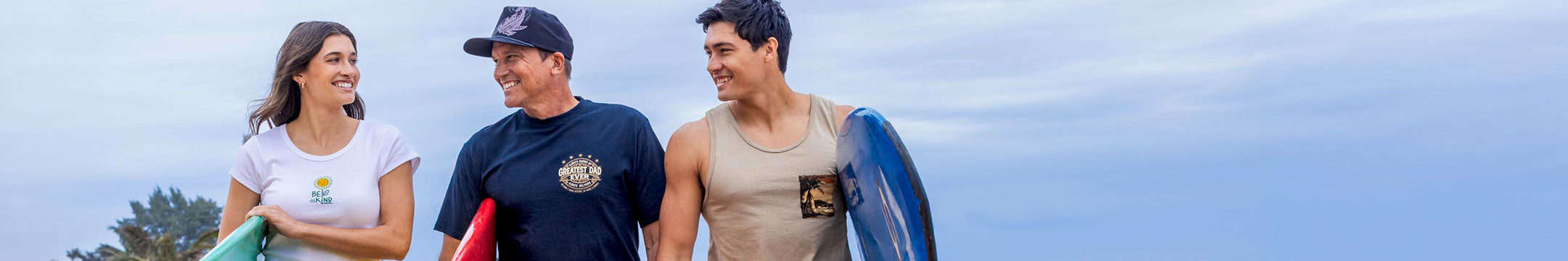 Three people with surfboards standing together against a clear sky.