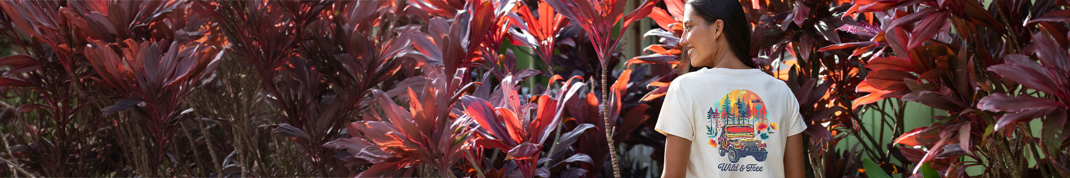 Person standing among dark red and green foliage