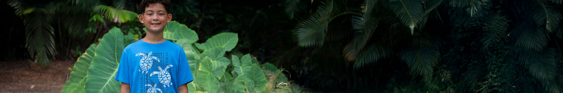 Child wearing a blue t-shirt with turtle design in a natural setting