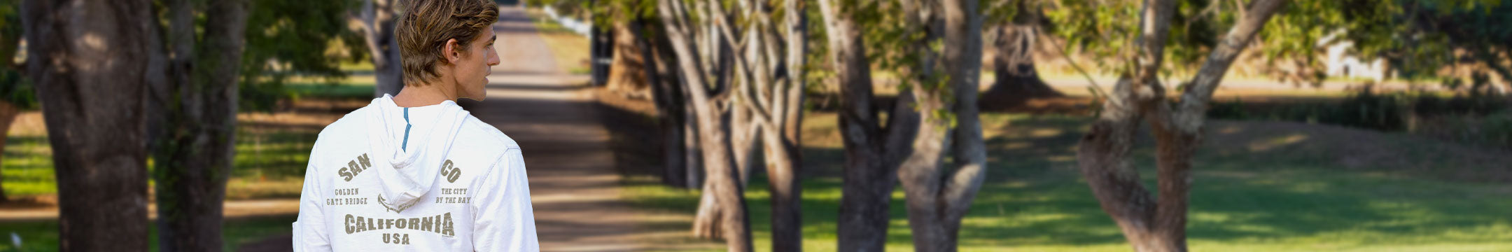Person wearing a white t-shirt with text in a park setting