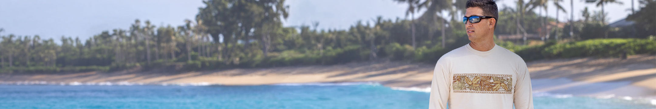 Man standing on a beach with clear blue water and palm trees in the background