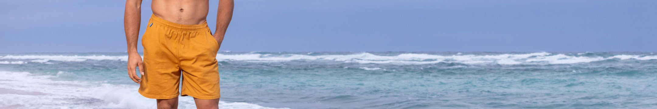 Person wearing yellow shorts standing on a beach with ocean waves in the background