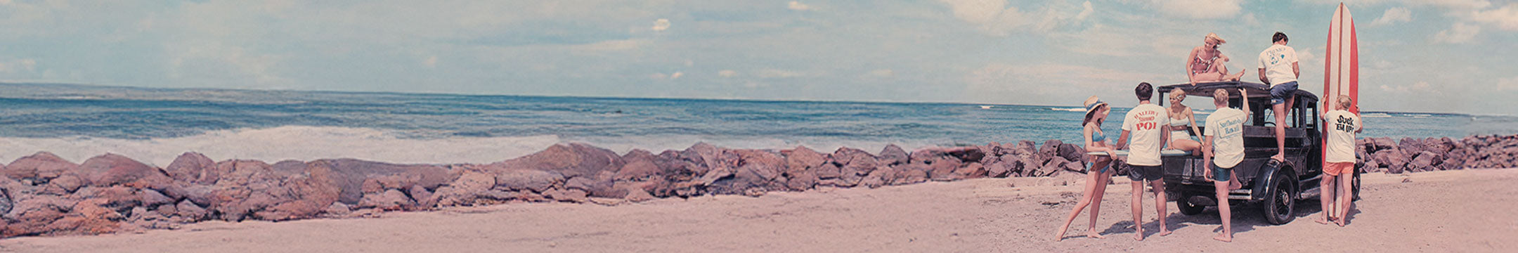 People by a vehicle on a beach with ocean and sky in the background