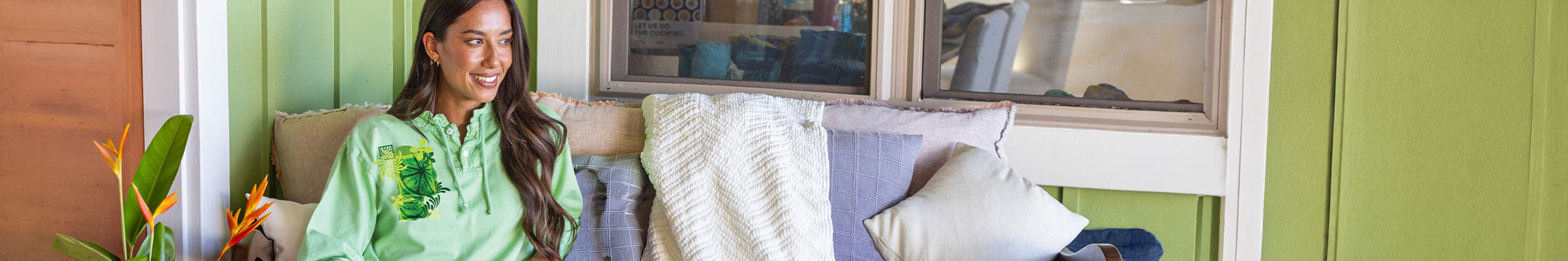 Woman in a green lightweight pullover sitting on a couch in a living room.