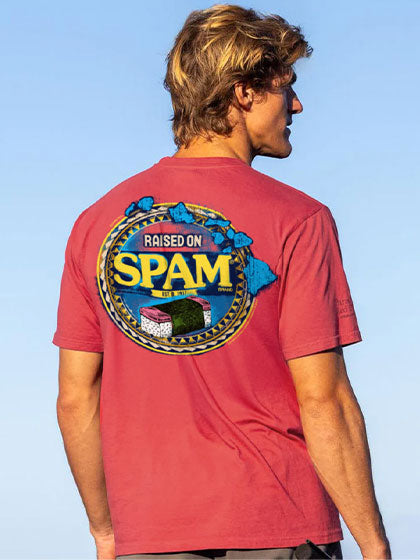 Person wearing a red t-shirt with 'Raised on Spam' graphic against a clear blue sky