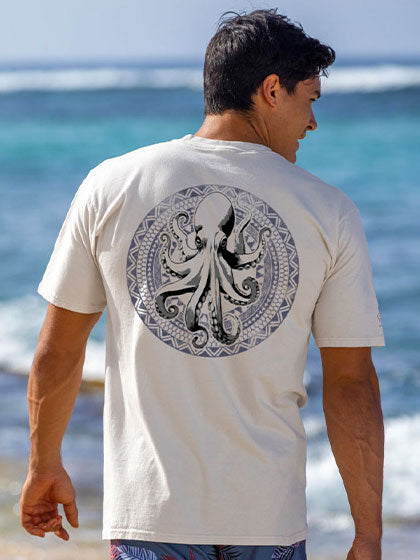 Man wearing a white t-shirt with an octopus design by the ocean