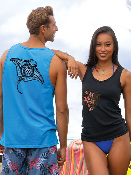 Man and woman standing together on a beach, wearing sleeveless tops with manta ray designs.