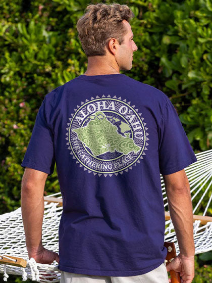 Man wearing a navy blue t-shirt with a green graphic and 'Aloha O'ahu' text on the back, standing outdoors.