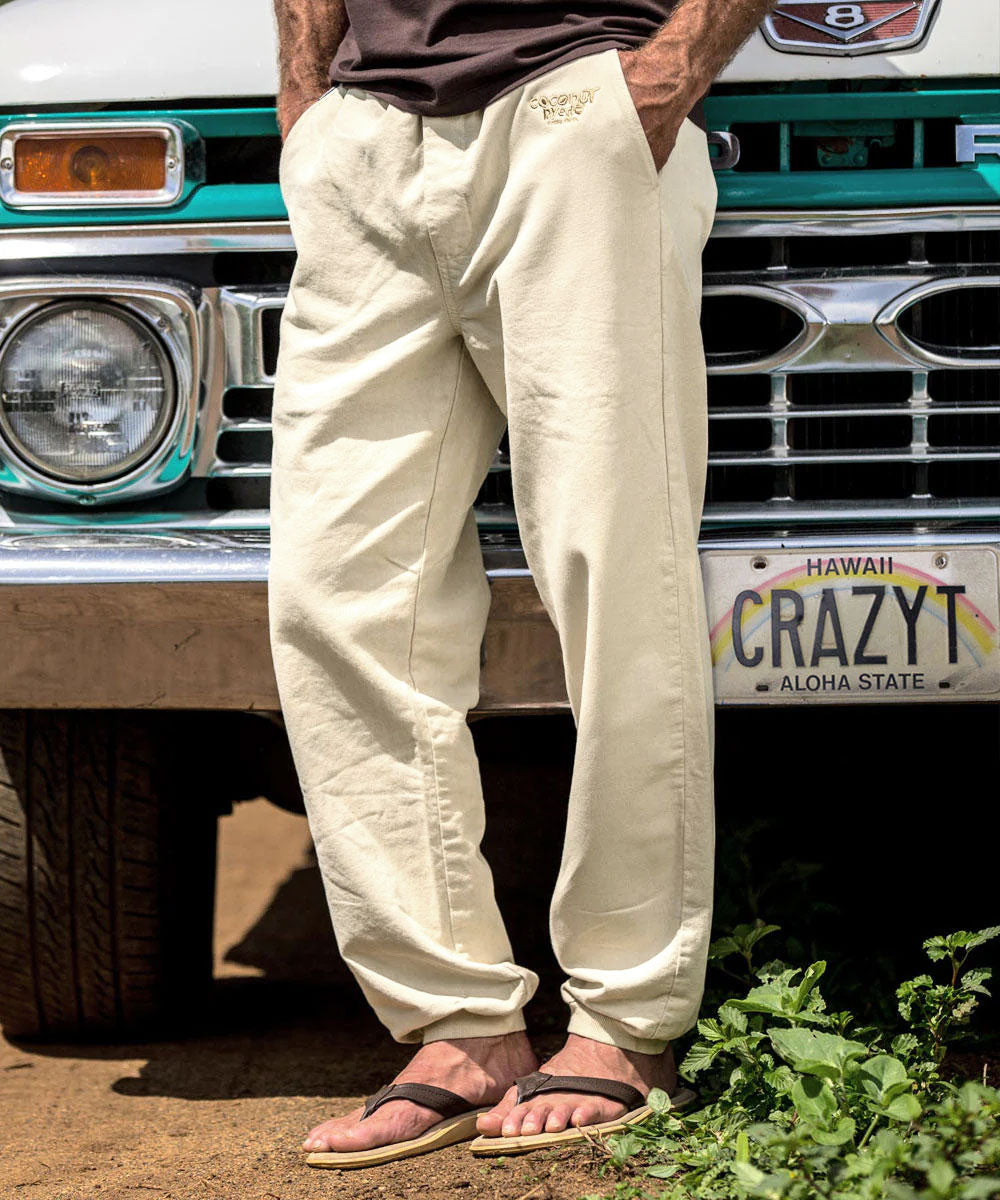 A person standing in front of a vintage truck wearing beige pants and brown sandals. The pants are dyed and have a relaxed fit with a banded rib-knit elastic waistband and cuffs.