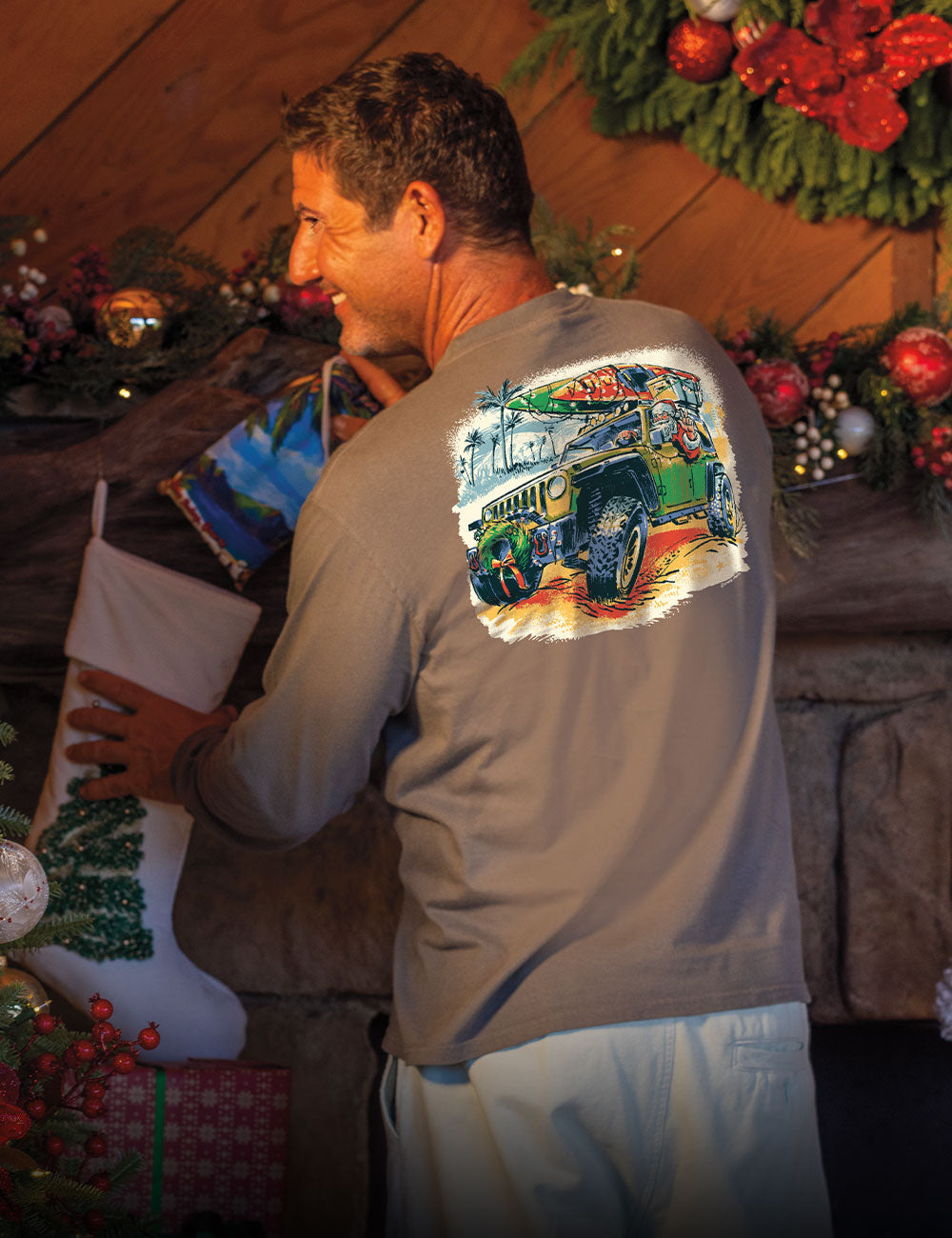 Man wearing a shirt with a colorful graphic, standing in a festive indoor setting with Christmas decorations.