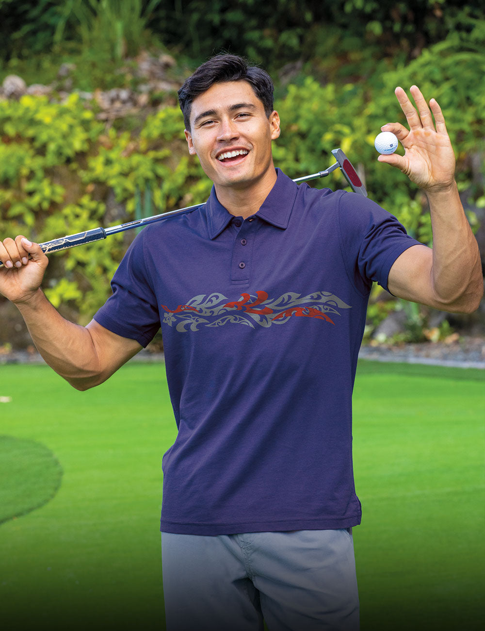 Man in a blue golf shirt holding a golf club and ball on a golf course