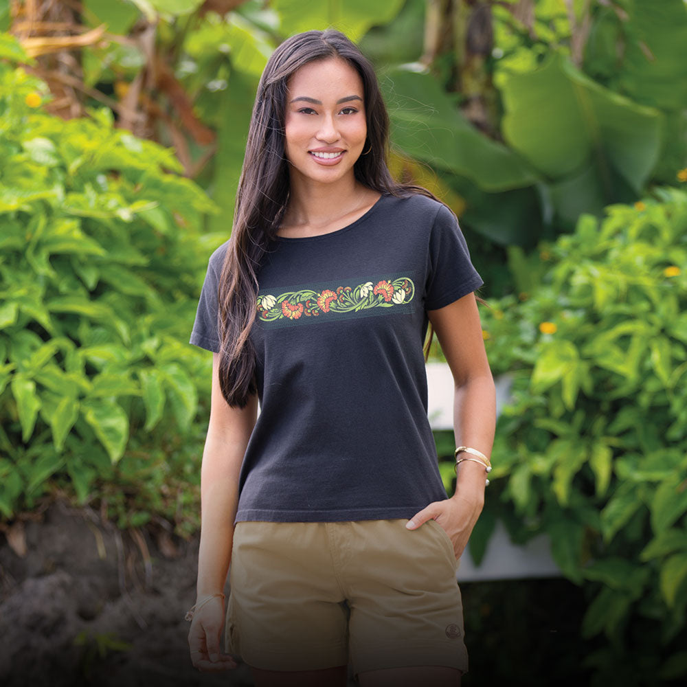 Woman wearing a black t-shirt with a floral design in a garden setting