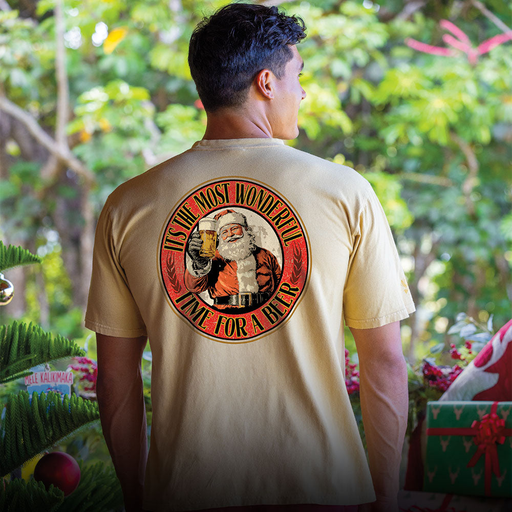 Person wearing a t-shirt with a festive design featuring Santa Claus and text, standing outdoors.