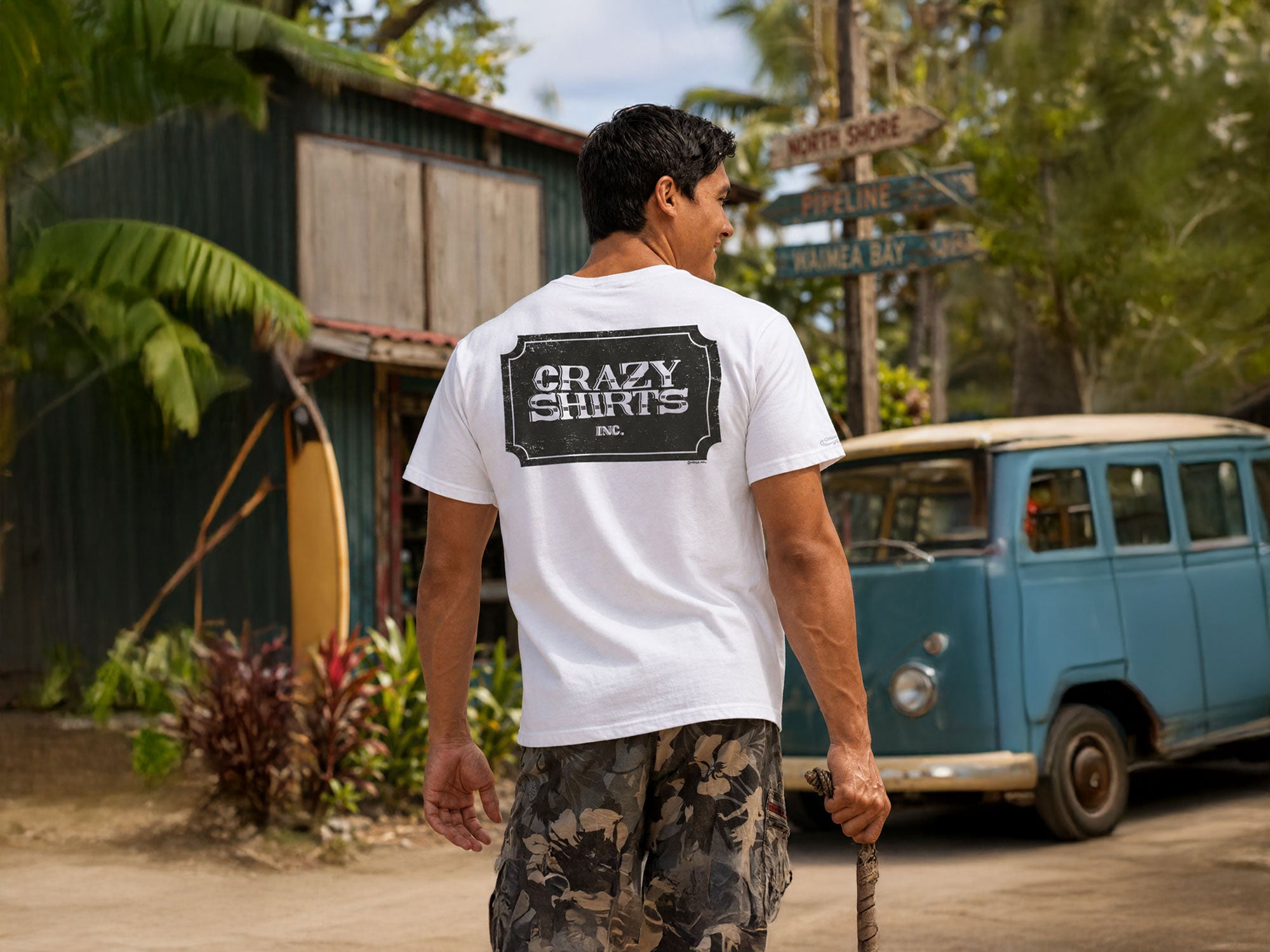 Man wearing a white t-shirt with 'Crazy Shirts Inc.' on the beach