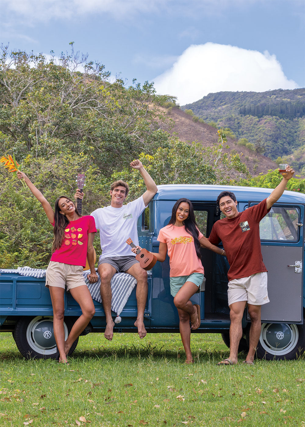 Four people posing in front of a blue truck with a mountainous background