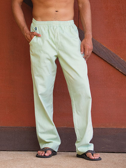 Person wearing surf spray twill pants standing against a red wall.