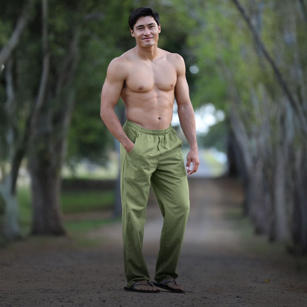 Man wearing green pants standing in a natural setting with trees.