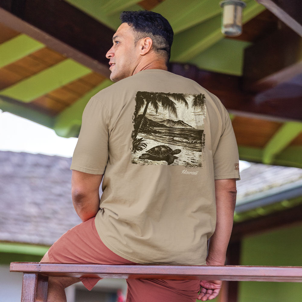 Man wearing a beige t-shirt with a turtle graphic sitting on a bench.