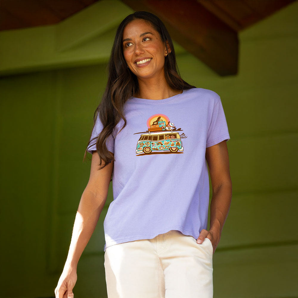 Woman wearing a light purple t-shirt with a colorful graphic design, standing against a green background.