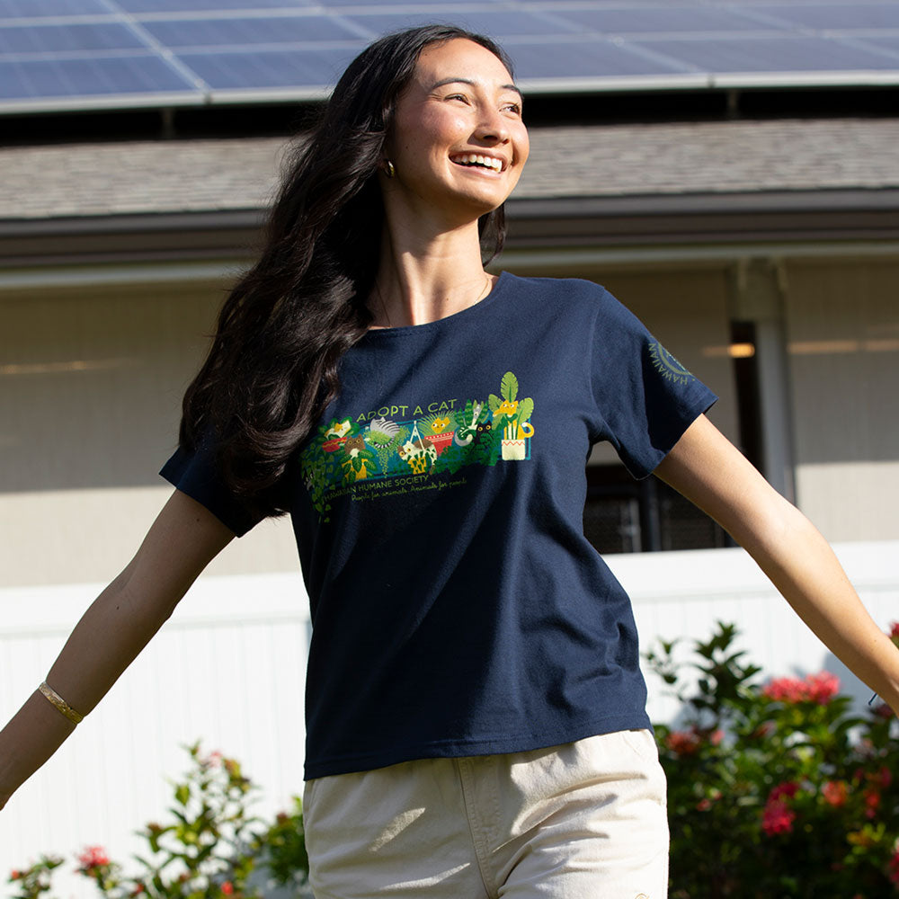 Woman wearing a blue t-shirt with a colorful design, standing outdoors with solar panels on the roof.