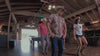 A group of 4 people line dancing inside a barn 