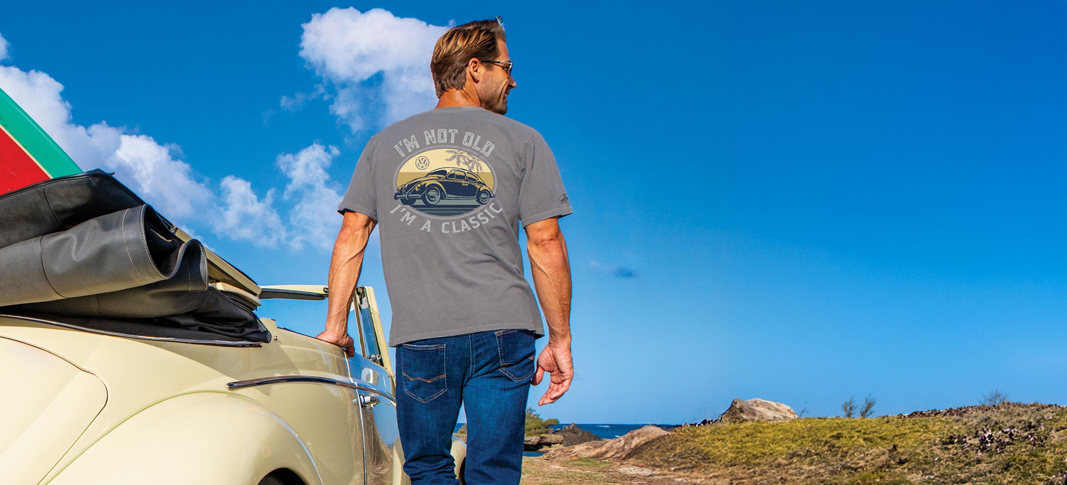 Man standing next to a vintage car with a scenic background