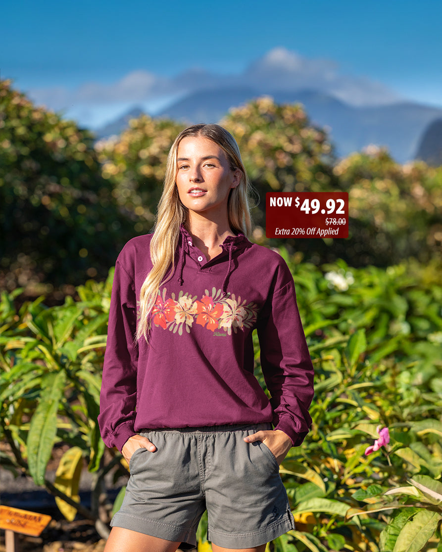 Woman wearing a purple hoodie with floral design in an outdoor setting with mountains in the background.